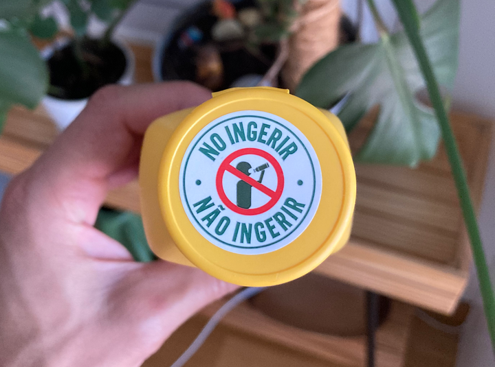 A sticker on the cap of a bottle with the text "Do not drink" in Portuguese and Spanish